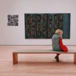 QR Code next to a painting and person sitting on a bank